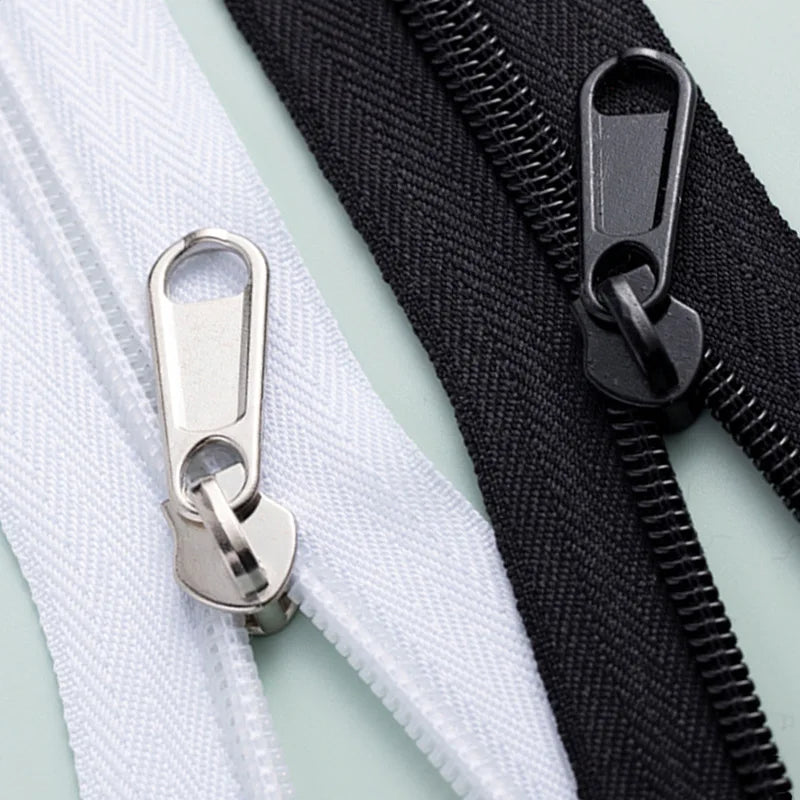 A close-up of a black zipper with a silver replacement slider and a white zipper tape.