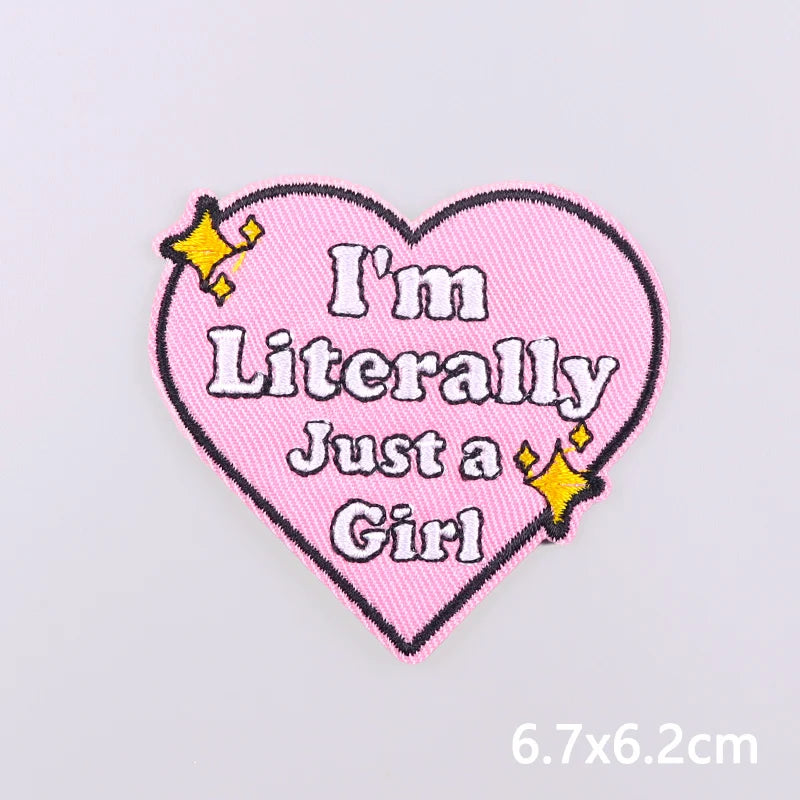 Pink heart shaped embroidery patch with text I'm Literally Just a Girl in black and yellow thread