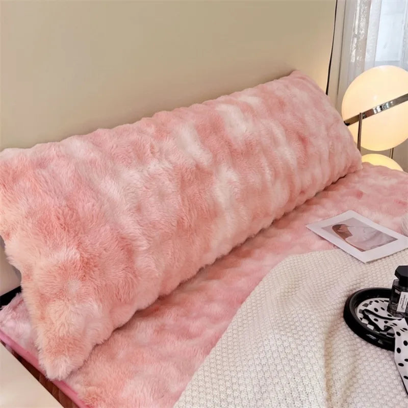 A pink plush long pillowcase resting on a light-colored surface.