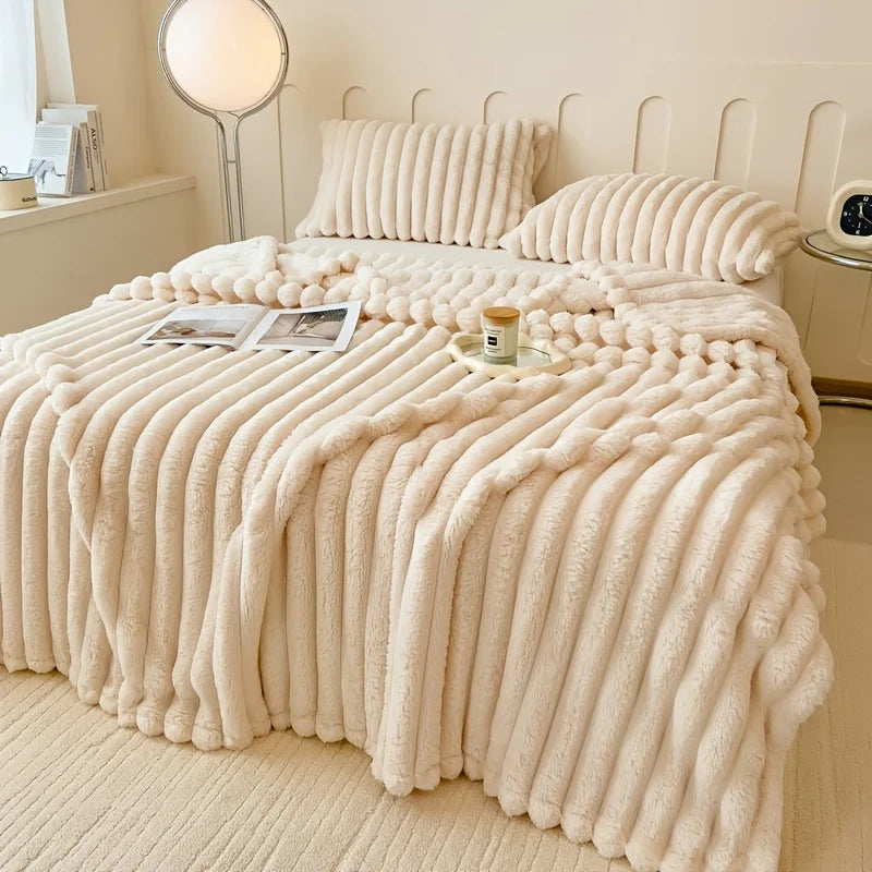 A thick, cream-colored striped flannel blanket is draped over a bed, featuring vertical ribbed texture.
