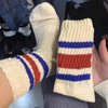 A close-up of a pair of white and blue striped crew socks with a ribbed texture.