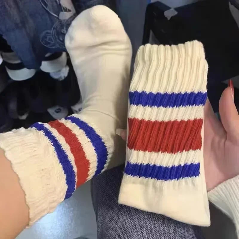 A close-up of a pair of white and blue striped crew socks with a ribbed texture.