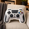 A white and gray gamer controller plush toy resting on a beige sofa cushion.