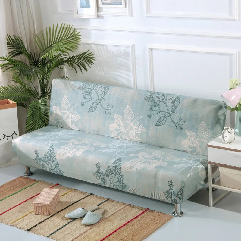 Light blue geometric print spandex slipcovers on a sofa bed with potted greenery and wooden accessories.