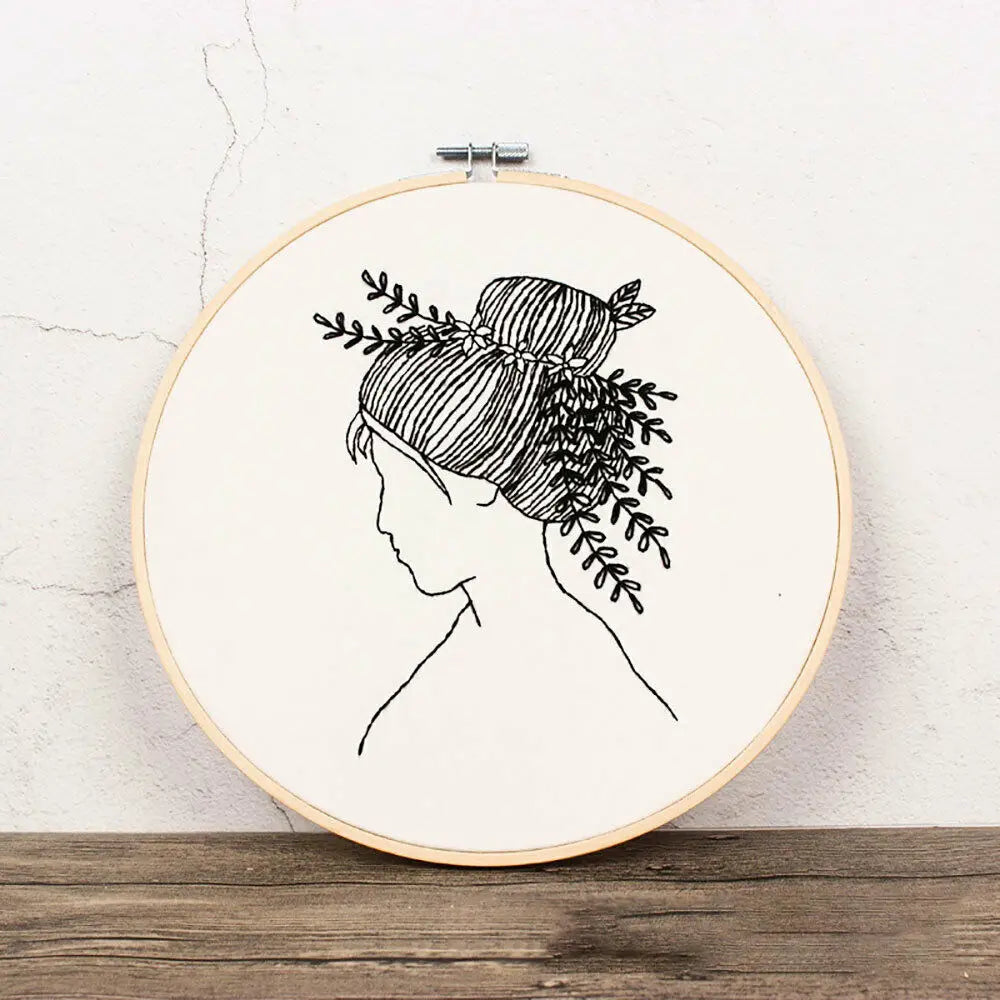 Black and white line drawing of a woman's profile with hair adorned by leafy branches