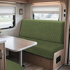 Interior view of an RV featuring a green cushioned dinette seat and a light wood table.