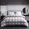 A luxury goose down duvet blanket displayed on a bed with a dark headboard and white bedding.