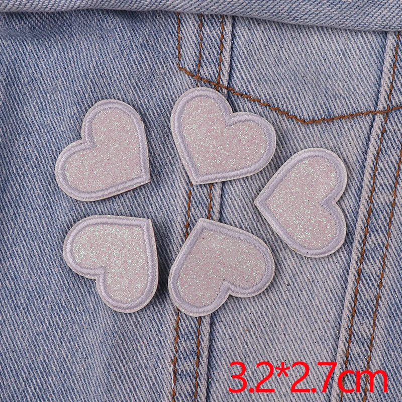 Five pink glitter heart star iron-on patches are displayed on a denim fabric background.