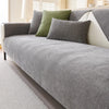A gray sofa protection cover with olive green pillows on a light-colored sofa.
