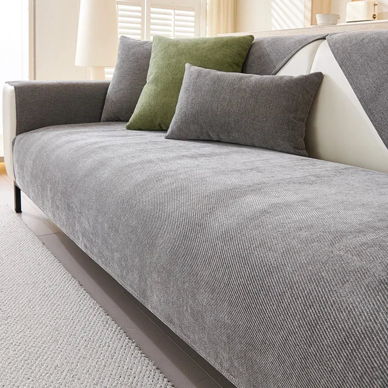 A gray sofa protection cover with olive green pillows on a light-colored sofa.