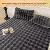 A dark gray knitted blanket or quilt with a textured surface and decorative pillows.