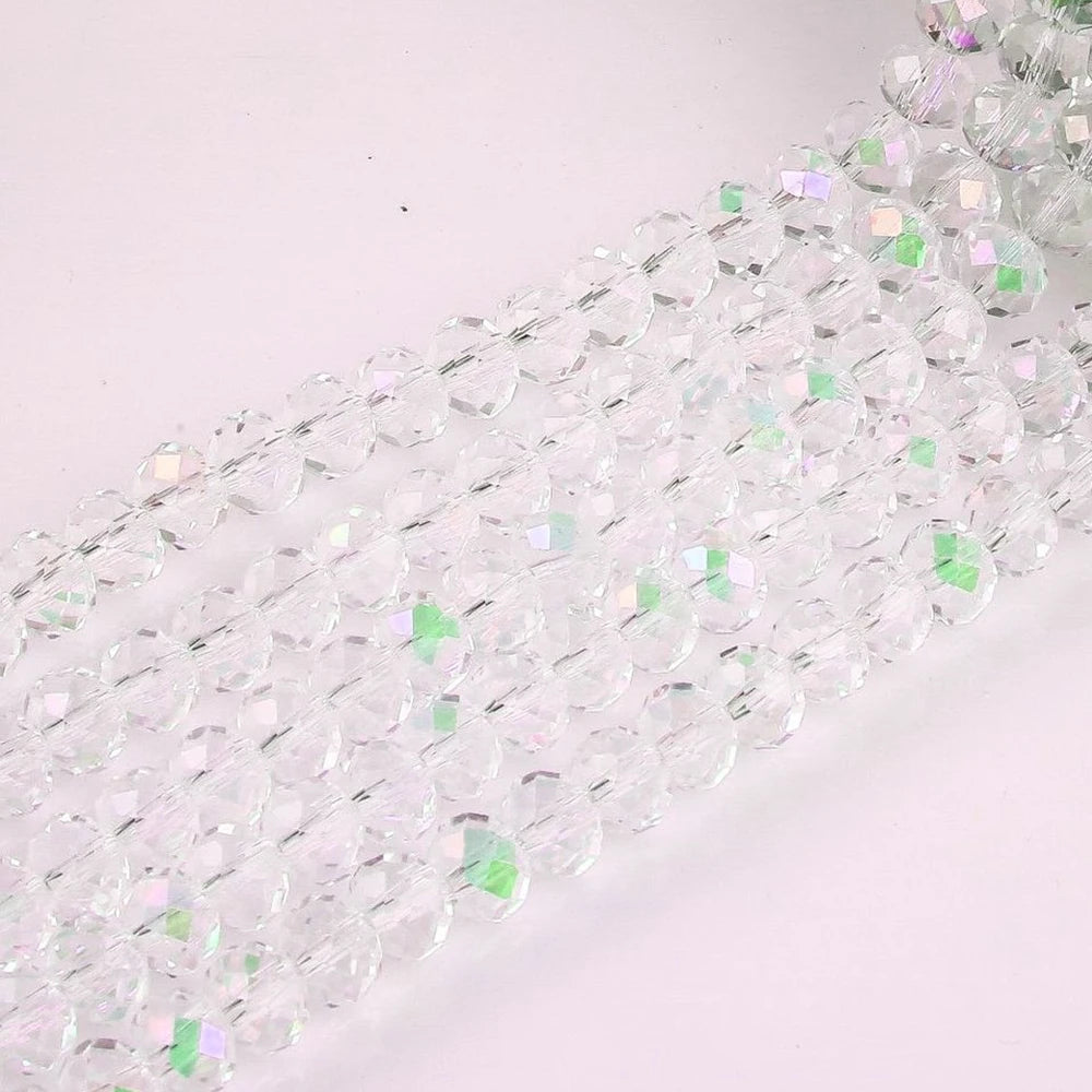 A close-up of clear faceted rondelle glass beads arranged in strands for crafting.