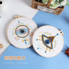 Handmade embroidery kit featuring two circular designs with eye patterns and star motifs on a blue background