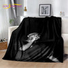 A black vintage-inspired graphic throw blanket draped over a white sofa.