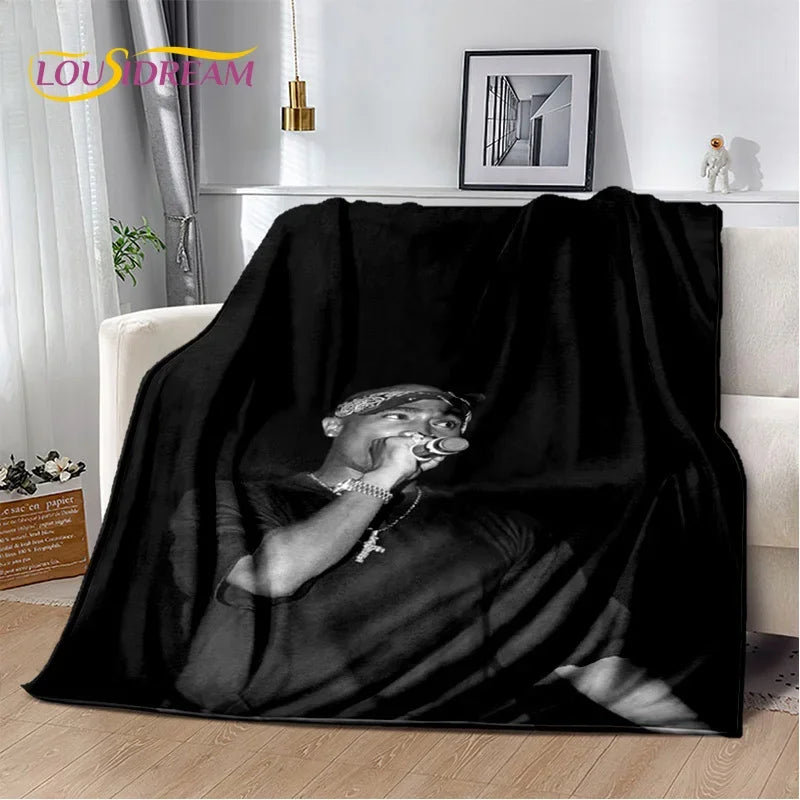 A black vintage-inspired graphic throw blanket draped over a white sofa.