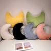A collection of moon-shaped throw pillows in yellow, green, black, blue, and pink resting on a white sofa.