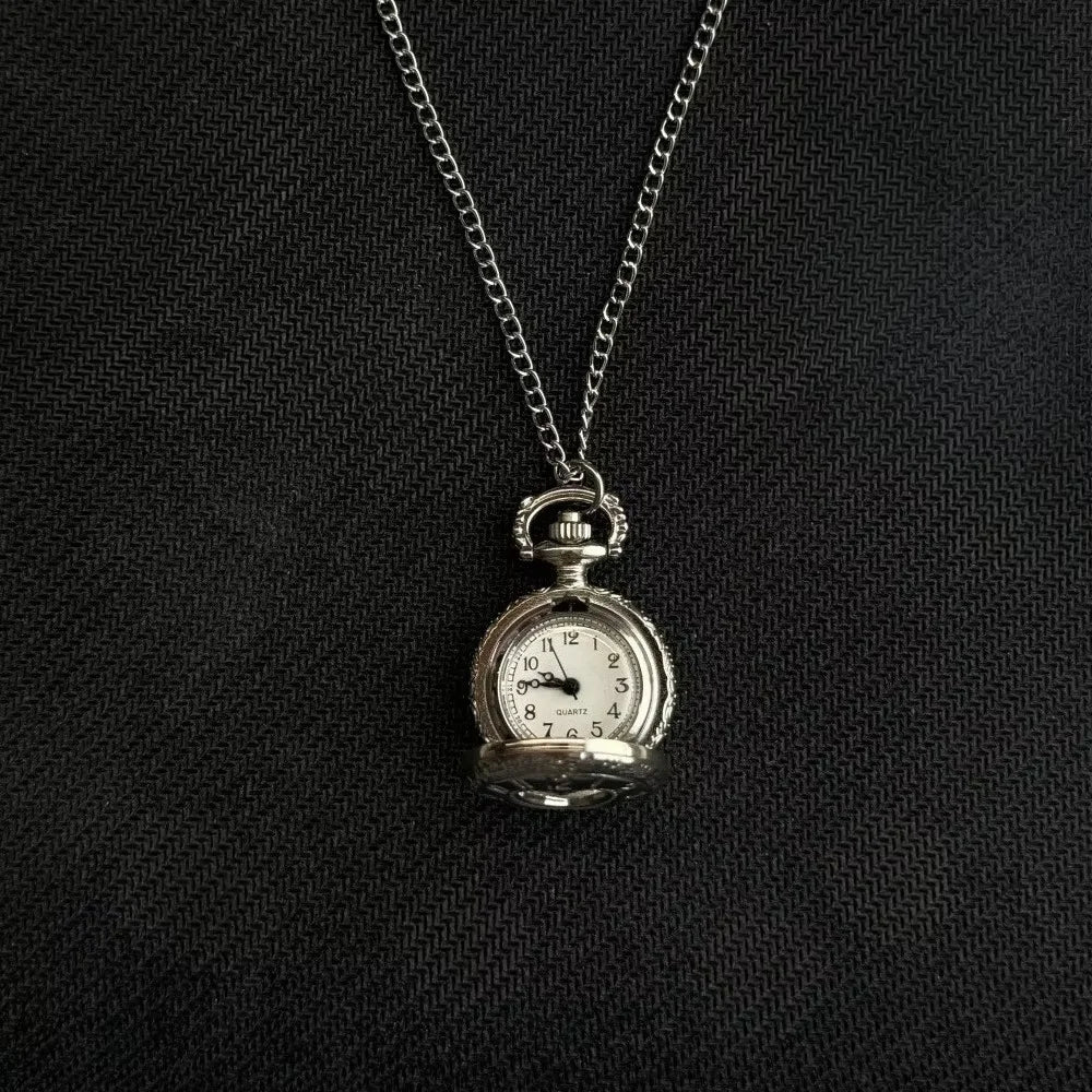 Silver pocket watch keychain with a chain and adjustable clock face against a black background