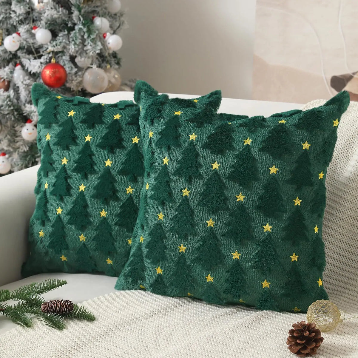 A pair of dark green knitted Christmas cushion covers with gold star embroidery resting on a white surface.