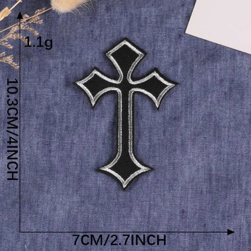 A black and white cross embroidery patch on a dark blue fabric.