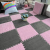 A square plush interlocking puzzle rug mat featuring pink and gray diamond patterns with a small blue flower arrangement.