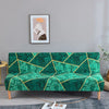 A teal geometric print spandex slipcover on a sofa bed with a gold accent, displayed in a modern living room.
