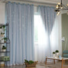 Light blue sheer curtains with a star pattern hanging in a bright room.