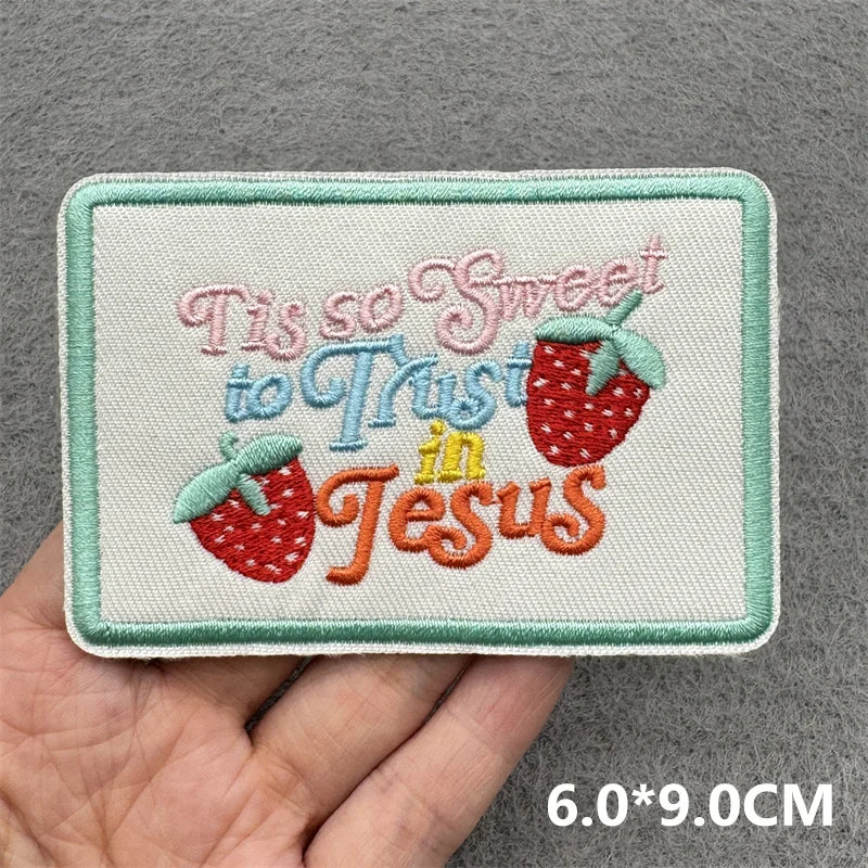 Pink embroidered patch with the text This so sweet to trust in Jesus on a light green fabric background