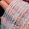 A hand holds a strand of clear pink faceted rondelle glass beads for crafting.