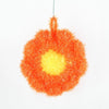 A bright orange flower-shaped kitchen dish scrubber sponge with a yellow center.