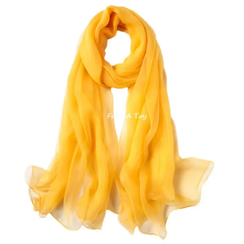 A bright yellow silk scarf draped and folded, suitable for sensory play.