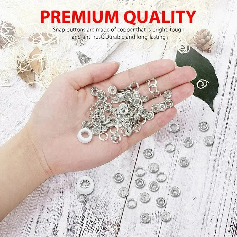 A hand holds a collection of silver metal prong rings and snap buttons for DIY sewing tools.