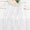A white marble-textured cheesecloth table runner decorated with pink flowers and gold cutlery.