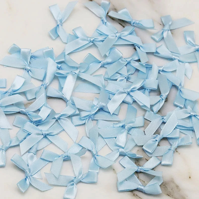 A scattered collection of light blue satin ribbon bows for crafts and decor.
