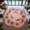 A round pink rug with a koi fish pattern and green plants is placed on a wooden floor.