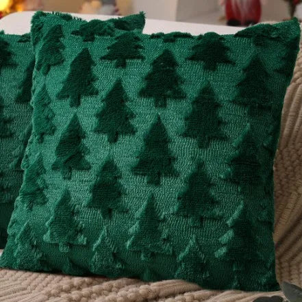 A dark green knitted cushion cover featuring a repeating pattern of evergreen trees.