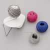 A hand operated wool yarn winder showing various spools of gray, pink, and blue yarn.