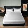 A luxurious white satin bedding set is displayed on a black bed with dark upholstery and modern decor.