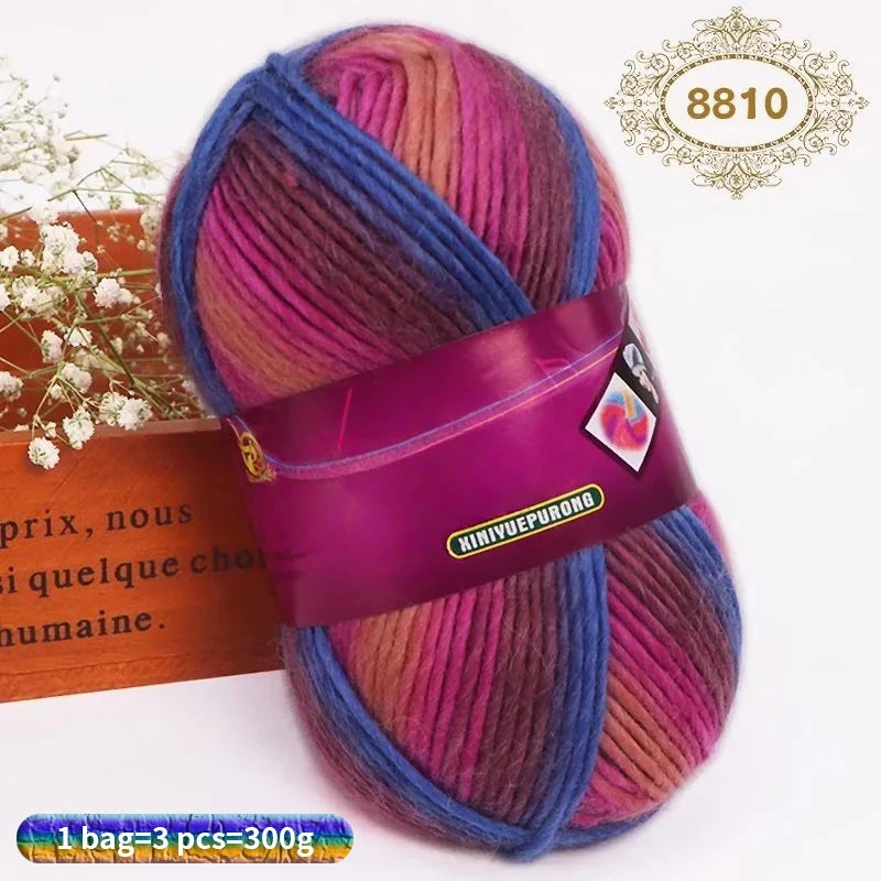 A ball of gradient dyed wool yarn in shades of pink, purple, and blue, tied with a purple ribbon.