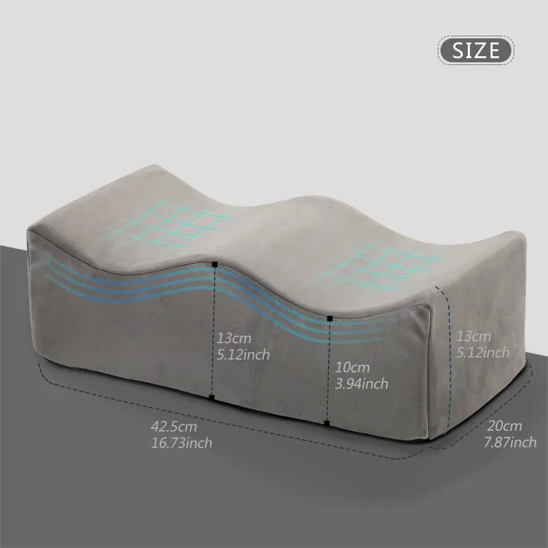 A beige ergonomic memory foam leg support pillow shown from the side with dimensions labeled.