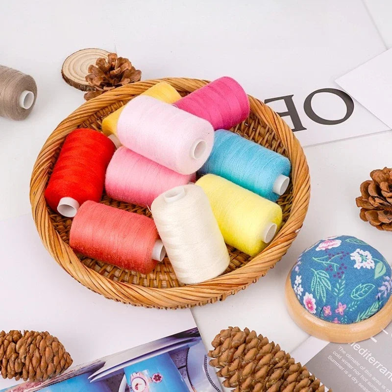 A wooden bowl filled with ten rolls of colorful polyester sewing thread in various shades of pink, yellow, red, and blue.