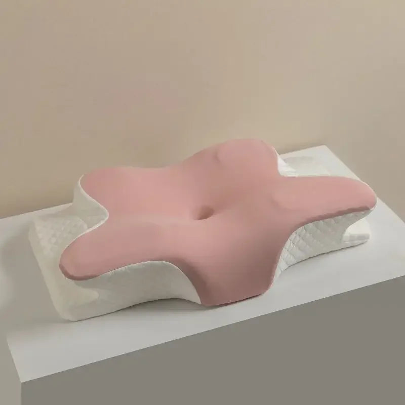 A pink cooling memory foam pillow with a butterfly shape and neck support is displayed on a white surface.
