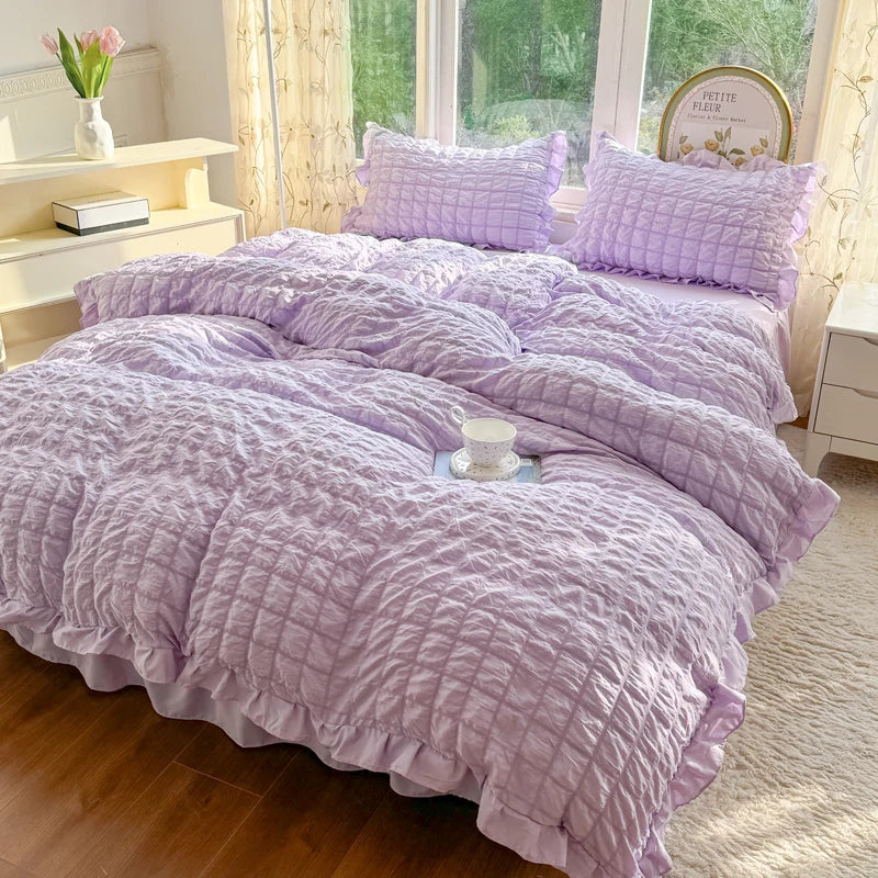 A lilac lace seersucker duvet cover set displayed on a bed with matching pillows and a decorative sign.
