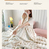 A person is relaxing on a bed covered with a fluffy white rabbit fur throw blanket.