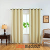 Cream blackout curtains hanging in a window with wooden furniture and a plant visible.