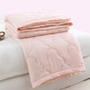 Pink quilted duvet cover folded on a white surface