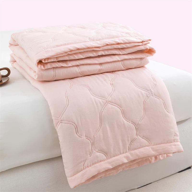 Pink quilted duvet cover folded on a white surface