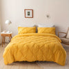 A bright yellow quilted bedspread covers a bed with white pillows and wooden bedside tables.