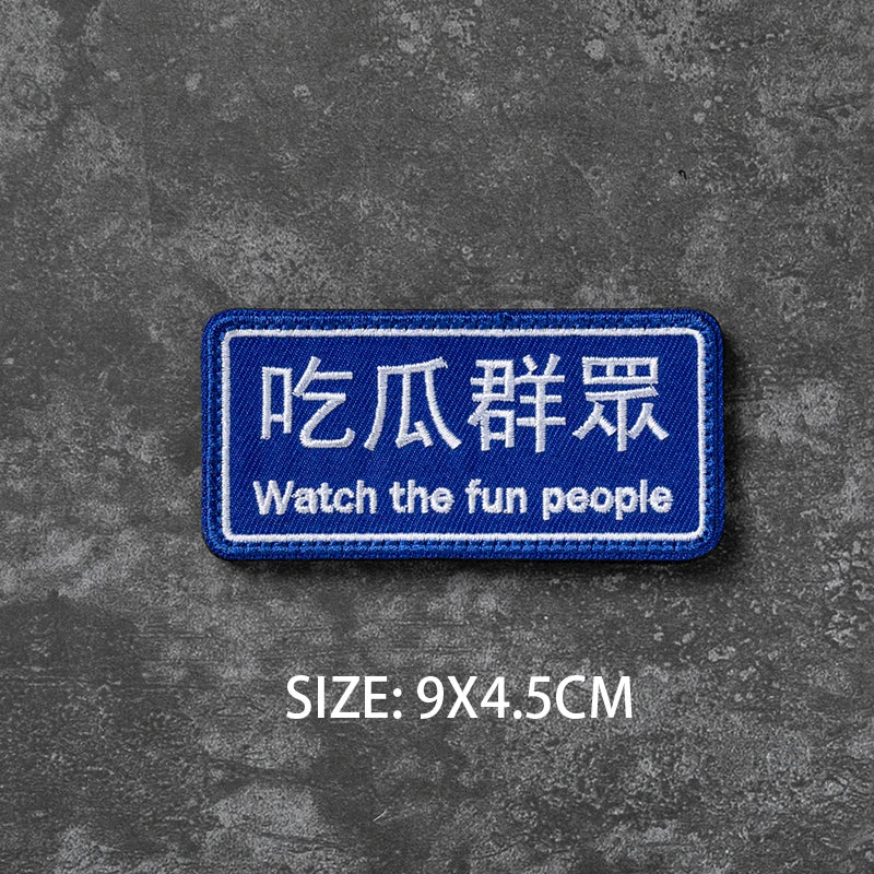Blue embroidered badge with Chinese text and English translation for watching fun people
