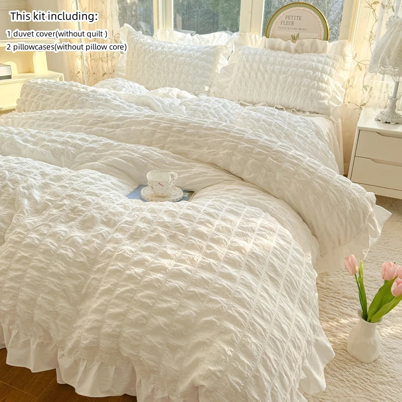 A white lace seersucker duvet cover set including a duvet cover and two pillowcases displayed on a bed.