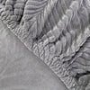 Close-up texture of a gray jacquard stretch sofa cover with a ruffled edge.